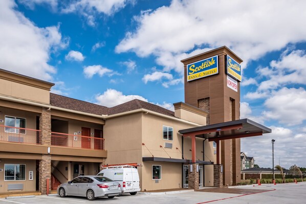 Un hotel con un letrero que dice 'Scotish Inn Suites' y una entrada cubierta.