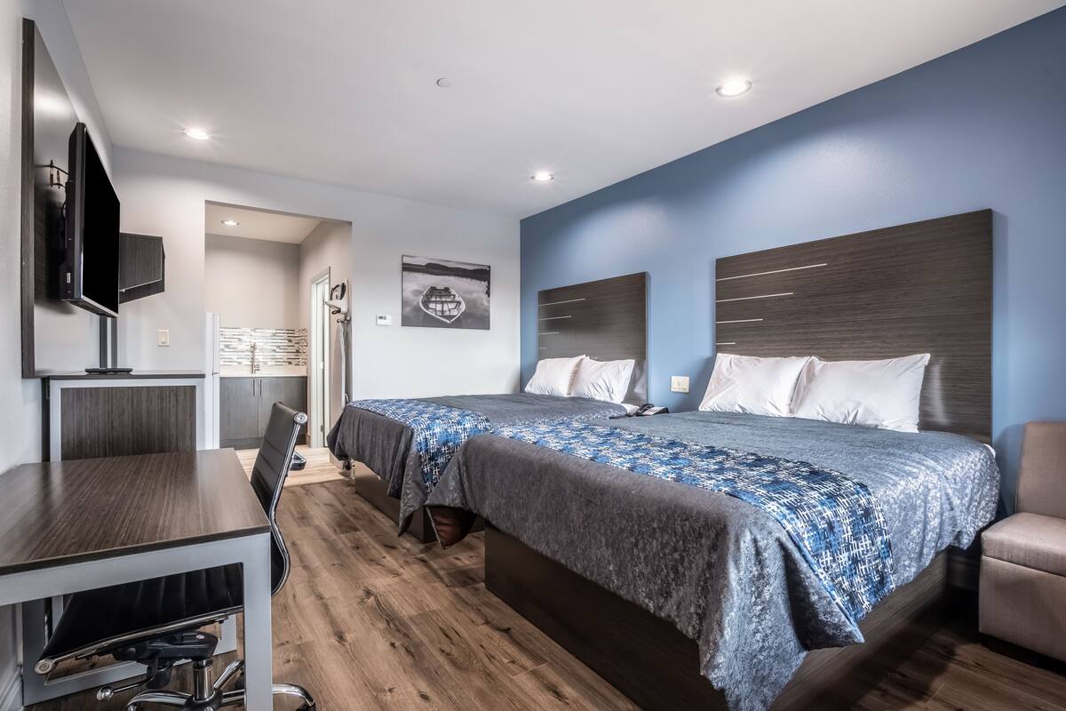 A modern hotel room with a large bed, a desk, and a TV.