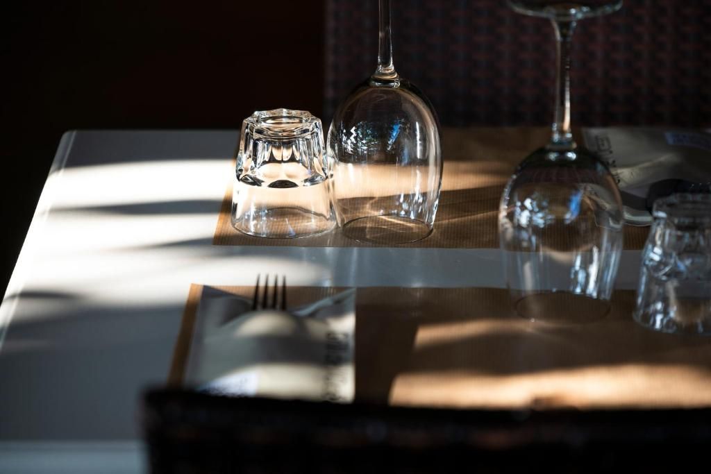 A table with a clear glass, a wine glass, and a salt and pepper shaker.