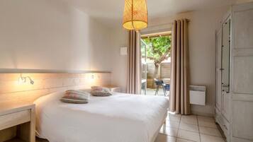 Un dormitorio con cama, mesita de noche, lámpara, armario y vistas al exterior.