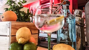 Un bar, avec un verre rempli de boisson, des citrons, des limes et des oranges disposés sur le comptoir.