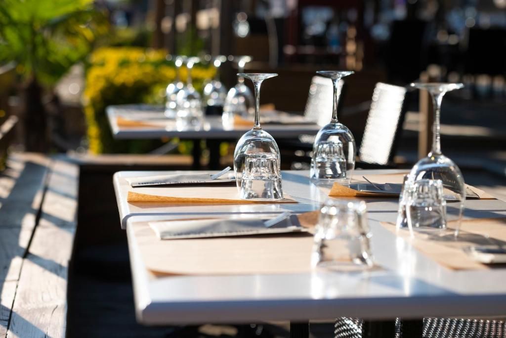 Une table à manger dressée avec des assiettes, des couverts et des verres à vin, ce qui évoque l’ambiance d’un restaurant.