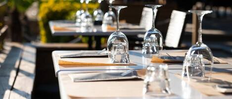 Mesa de comedor dispuesta con platos, cubiertos y copas de vino, evocando un ambiente de restaurante.