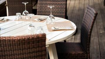 A round dining table with chairs, clear glassware, and a menu.