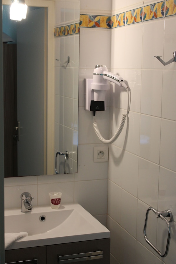 A bathroom with a white sink, a mirror, a towel, a hand dryer, and a towel rack. - Hotel Bar du Centre (Soustons)