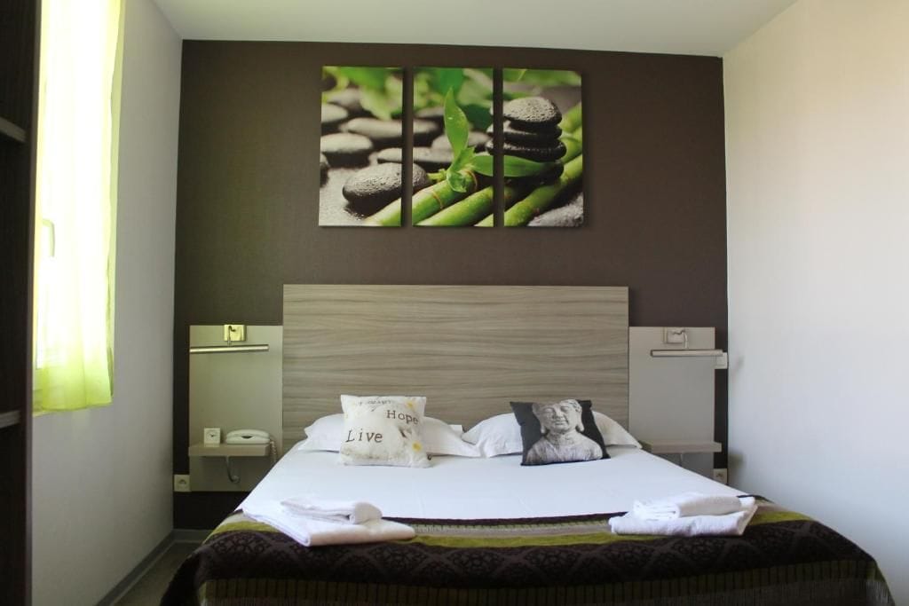 Een hotelkamer met een bed, nachtkastje en een kunstwerk aan de muur.