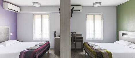 A room with two beds, a desk, and a chair. There are air conditioning units on the walls.