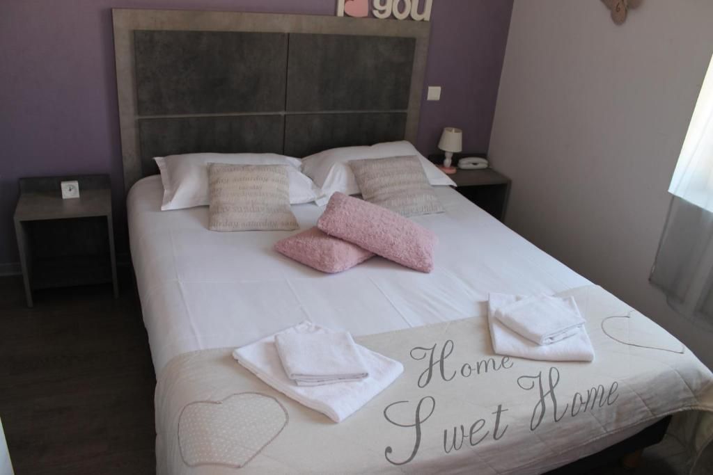 A neatly made bed with a 'Home Sweet Home' sign, a bedside lamp, and a nightstand with a phone.