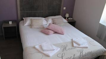 A neatly made bed with a 'Home Sweet Home' sign, a bedside lamp, and a nightstand with a phone.