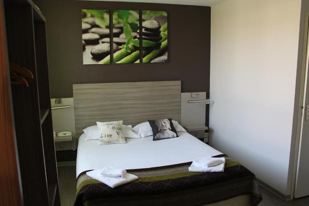 Una habitación de hotel con una cama, una mesita de noche, un teléfono y un cuadro en la pared.