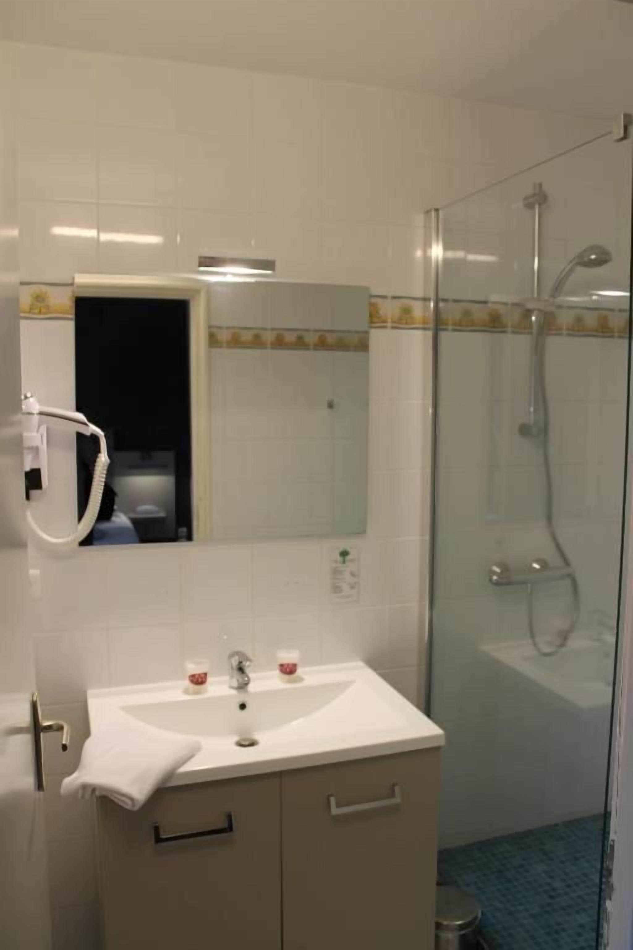 A bathroom with a sink, mirror, and shower.
