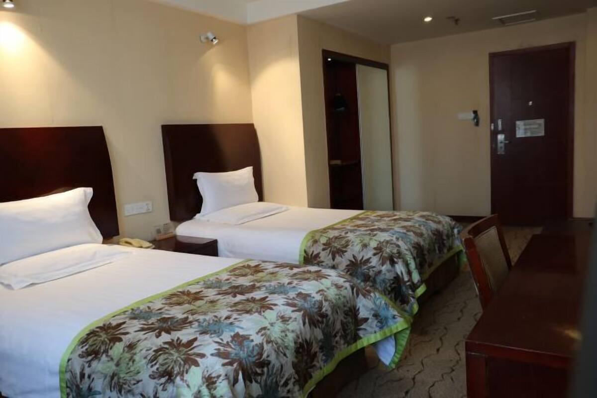 Ein Hotelzimmer mit zwei Betten, einem Holzkopfteil, einem Schreibtisch und einem Stuhl.