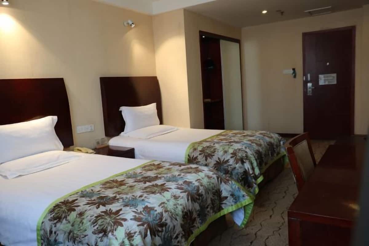 A hotel room with two beds, a wooden headboard, a desk, and a chair.