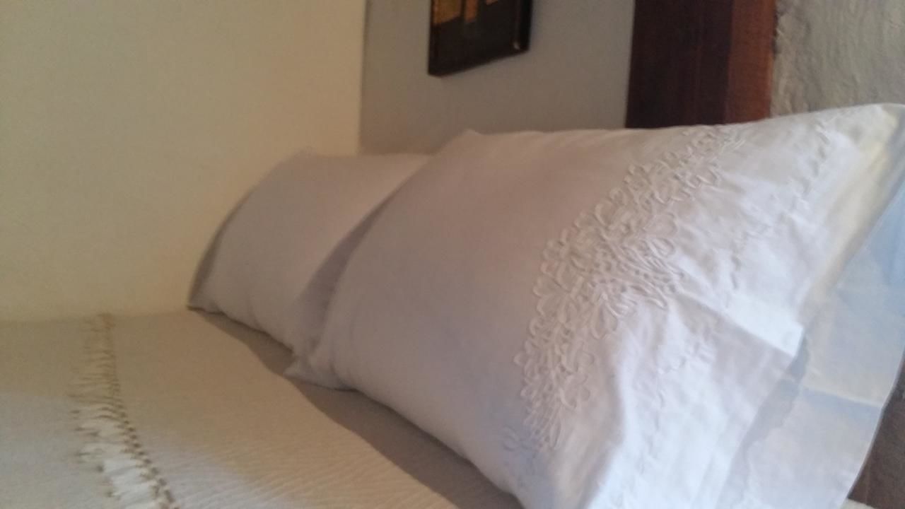 Een bed met witte lakens en een decoratief kussen.
