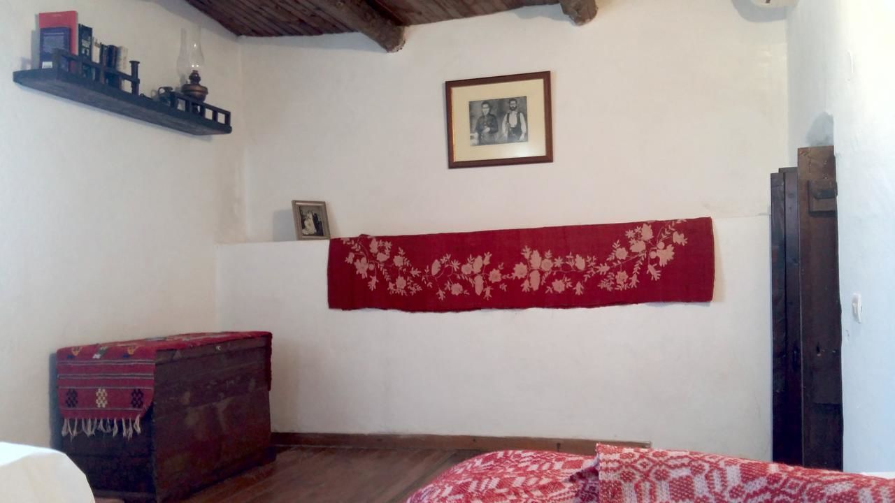 Een kamer met een houten plafond, een rood tapijt met patroon, een klein houten kistje en een lijst met een afbeelding aan de muur.
