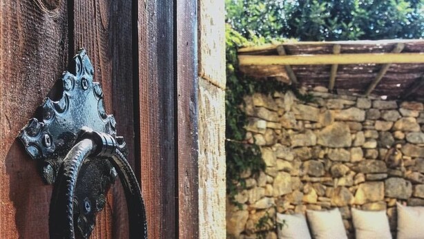 A rustic wooden door with a decorative metal knocker. - Bendeni Cottage (Chania)