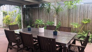 A covered patio with a glass-top table and six wooden chairs. - SHORE THING - FAMILY BEACH RETREAT  (Tootgarook)