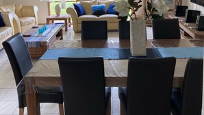 A spacious living room with a large window, a sofa, a dining table with chairs, and a TV. - SHORE THING - FAMILY BEACH RETREAT  (Tootgarook)