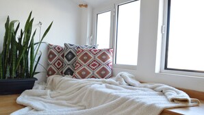 A bed with a white blanket, two patterned pillows, and a potted plant beside it. - Akti Posidonos (Agios Nikolaos)