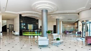 En rymlig entréhall med en receptionsdisk, sittgrupper och en modern design.