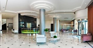 A spacious lobby with a reception desk, seating areas, and a modern design.