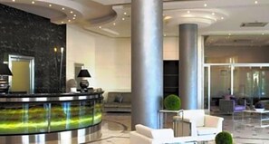 A modern lobby with a reception desk, seating area, and a large pillar.