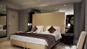 Ett modernt hotellrum med en stor säng, sängbord, en spegel och en sittgrupp med handdukar.