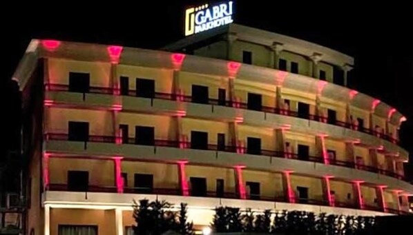 A multi-story hotel with balconies, a sign indicating it is a hotel, and a well-lit facade.