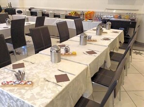 A banquet hall with long tables set for dining, equipped with cutlery, napkins, and condiments.