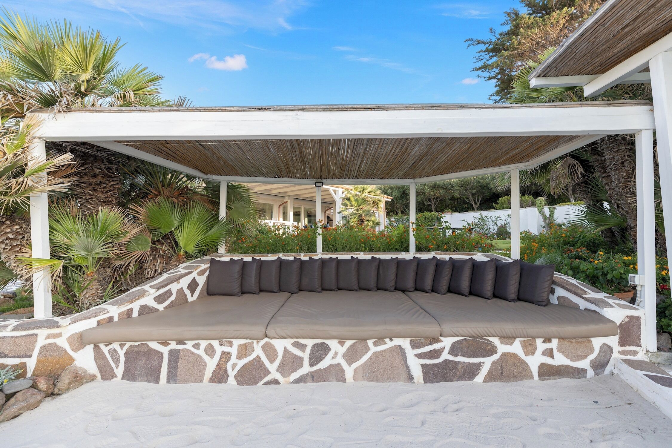 A covered outdoor seating area with stone walls and a wooden roof.