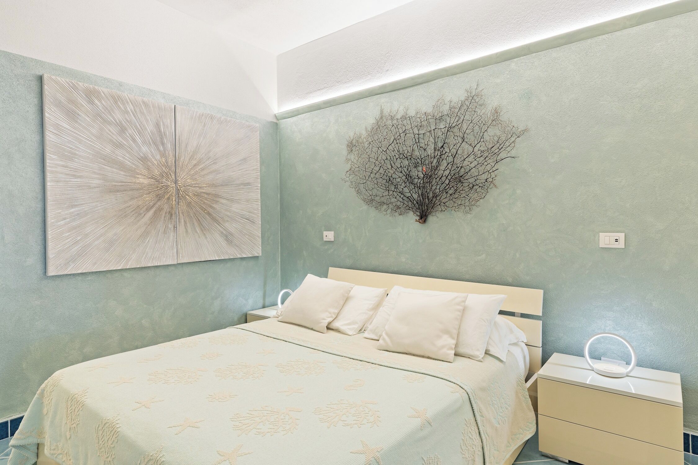 Een slaapkamer met een bed, nachtkastje en wanddecoratie.
