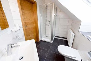 A bathroom with a shower, toilet, and sink.