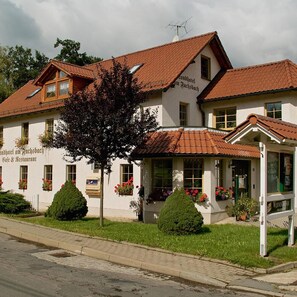 A two-story building with a red-tiled roof, multiple windows, and a sign indicating it is a hotel and restaurant. - Landhotel Am Fuchsbach (Berga/Elster)