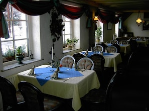 A restaurant with multiple tables set for dining, each with a tablecloth and cutlery. - Landhotel Am Fuchsbach (Berga/Elster)