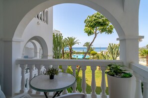 A balcony with a view of the sea, a pool, and tropical plants. - Stella Maris Beachfront B by Casasol (Nerja)