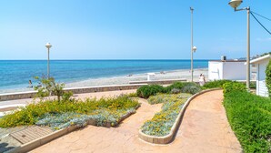 Une promenade en bord de mer avec un chemin pavé, des parterres de fleurs et des lampadaires.
