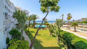 Une cour d’hôtel avec une piscine, des palmiers et une vue sur la mer.