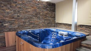 Een hottub in een houten blokhut met een achtergrond van een stenen muur.