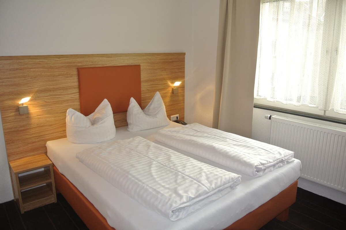 A double bed with two pillows and a wooden headboard.