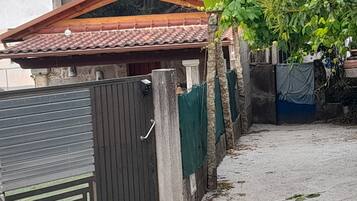 A gated area with a metal gate, a concrete pathway, and a building with a tiled roof.