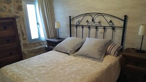Un lit avec une couvre-lit à motifs, une tête de lit ornée d’un décor et deux lampes de chevet.