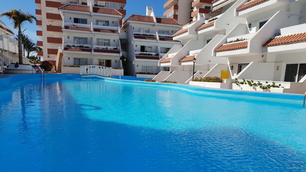 Une grande piscine entourée d’immeubles à plusieurs étages dotés de balcons.