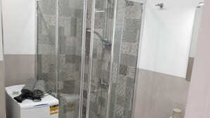 Une salle de bain moderne avec une douche à parois de verre, un lavabo blanc et des toilettes compactes.