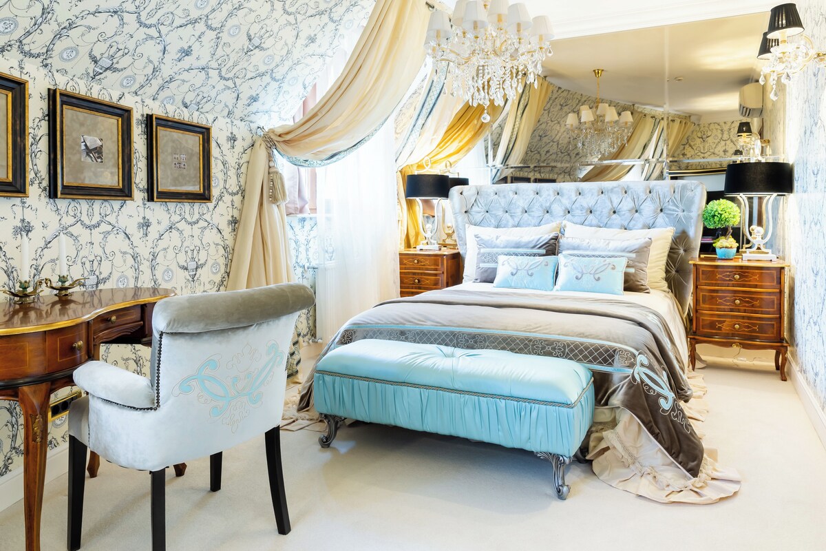Une chambre à coucher avec une tête de lit capitonnée, un bureau et une chaise.