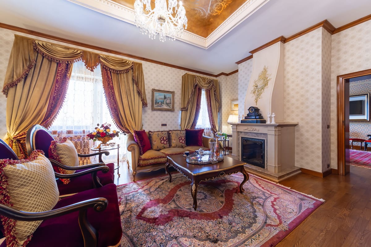 A traditional living room with a sofa set, a fireplace, and a chandelier.