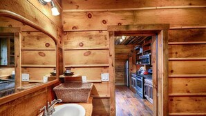 L’intérieur d’une cabane en bois comprend un évier en bois, un miroir et un coin cuisine avec une cuisinière et un réfrigérateur.