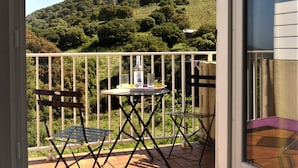 A balcony with a table, chairs, and a bottle of liquor. - Quiet apartment and grounds. Sea view and maquis (Cargèse)