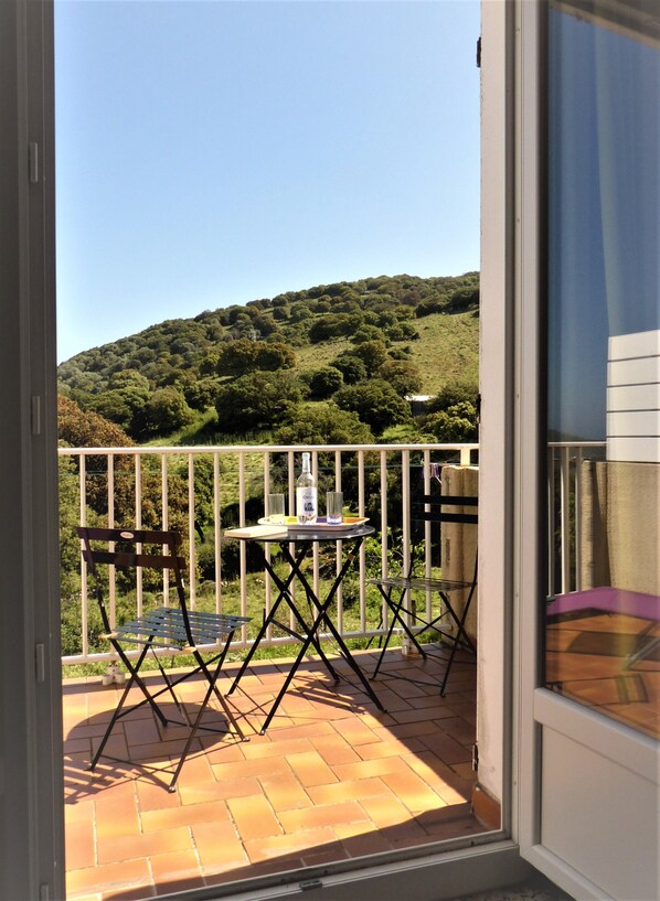 A balcony with a table, chairs, and a bottle of liquor.
