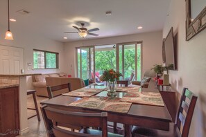 Enjoy meals with family and friends in this spacious living and dining area with a large window offering a view of lush greenery.
