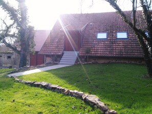 A house with a red roof, a stone pathway leading to the entrance, and a small tree in the front yard. - Pretty cottage F2 of 50m ² independent in Rouffach (Rouffach)